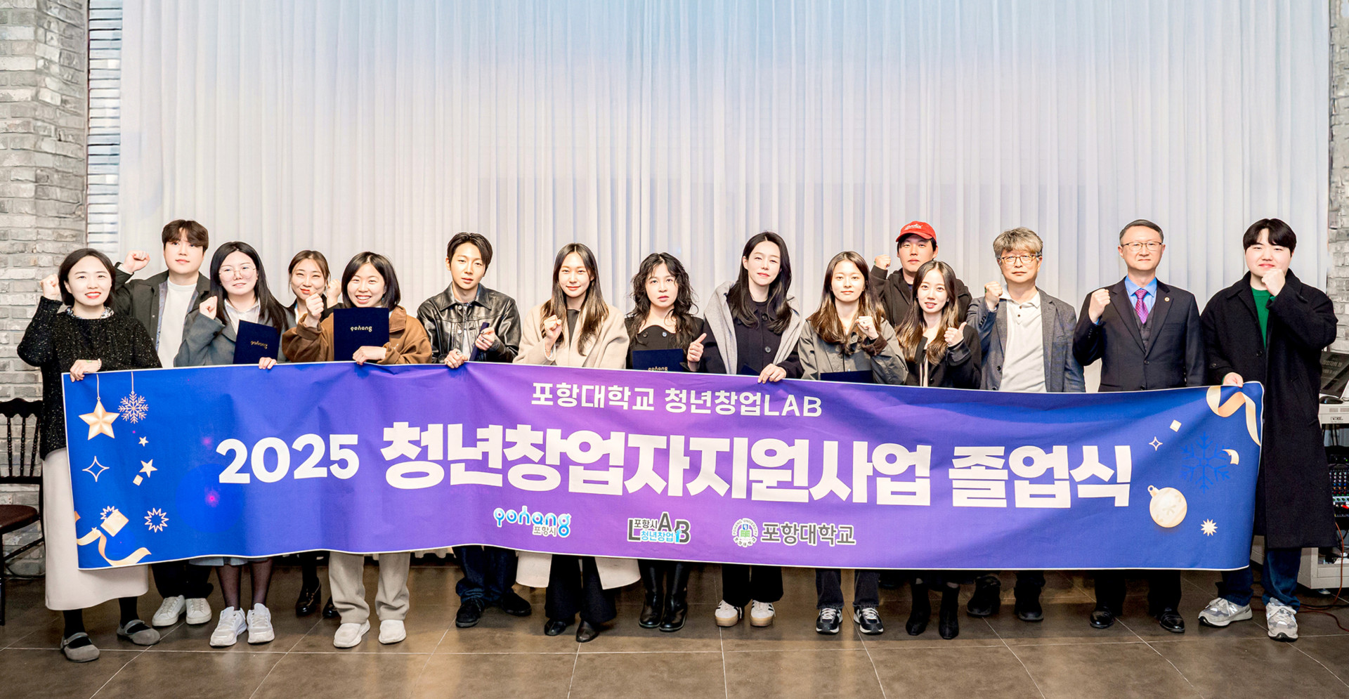포항대학교 청년창업LAB '2025 청년창업지원사업 졸업식' 기념사진입니다. 보라색과 파란색 그라데이션 배경의 대형 현수막에 '2025 청년창업지원사업 졸업식' 문구가 크게 적혀 있으며, 포항시, 포항시 청년창업LAB, 포항대학교 로고가 포함되어 있습니다. 현수막 뒤로 약 15명의 졸업생과 관계자들이 나란히 서서 오른손 주먹을 불끈 쥐고 파이팅 포즈를 취하며 성공적인 사업 마무리를 축하하고 있습니다.