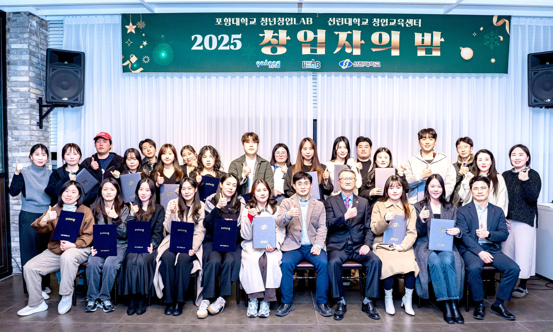 포항대학교 청년창업LAB과 선린대학교 창업교육센터가 함께하는 '2025 창업자의 밤' 기념 단체 사진입니다. 상단에는 초록색 배경에 '2025 창업자의 밤'이라고 적힌 현수막이 걸려 있습니다. 실내 행사장 브릭 벽면 앞에서 약 30여 명의 남녀 참가자들이 모여 있으며, 앞줄에 앉은 내빈들과 뒷줄의 청년 창업가들이 각자 수료증 또는 상장을 들고 엄지손가락을 치켜세우는 따봉 포즈를 취하며 밝게 웃고 있습니다.